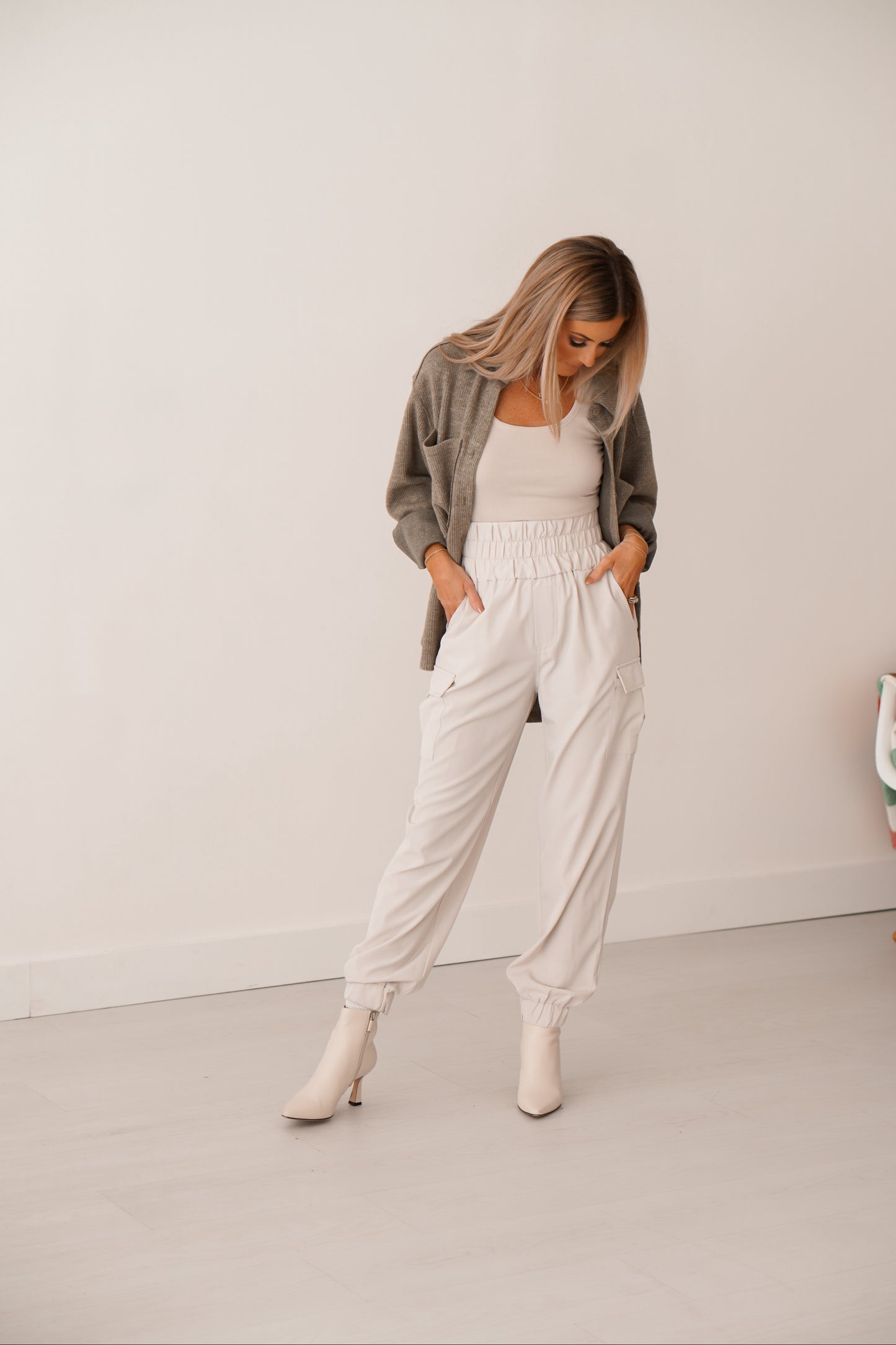 Blonde girl wearing cream cargo joggers with a cream tank and olive green shacket.