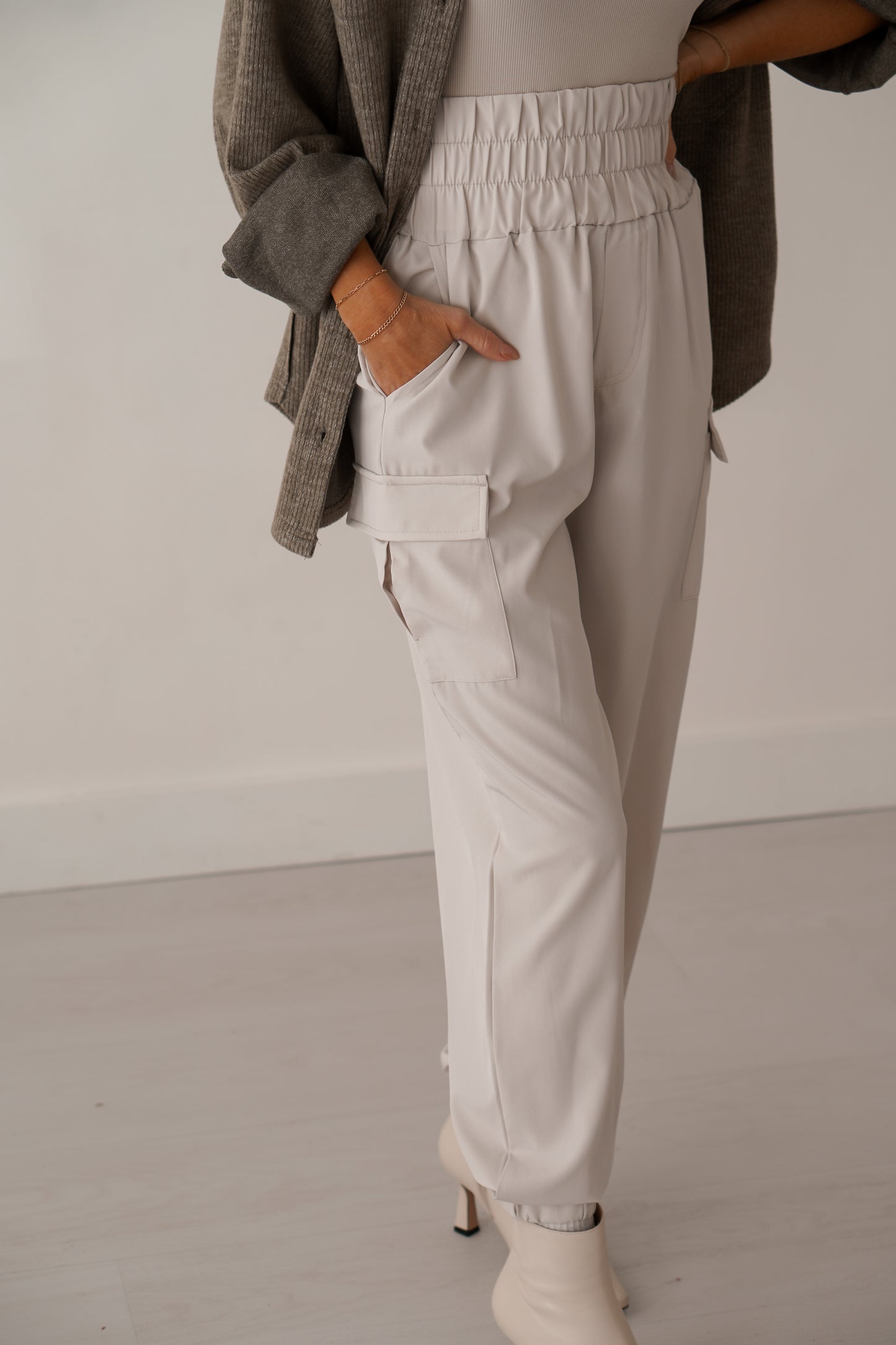 Up close of cream cargo joggers with her hand in pocket.