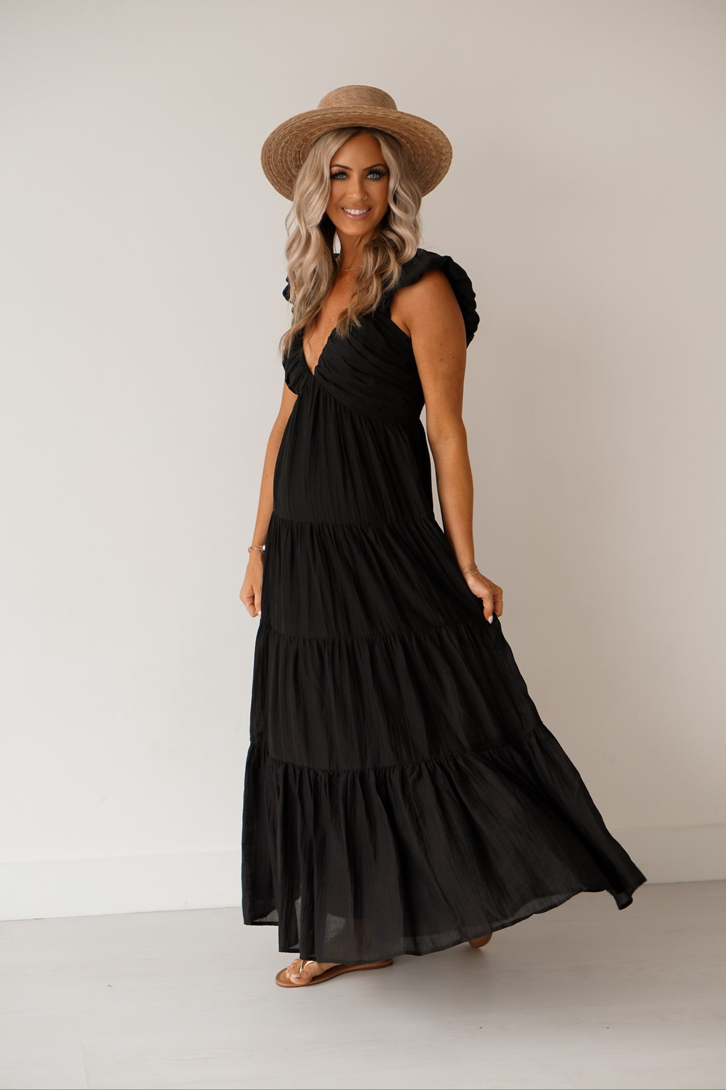 showing a side angle of the black maxi dress that has a v neck and has ruffles