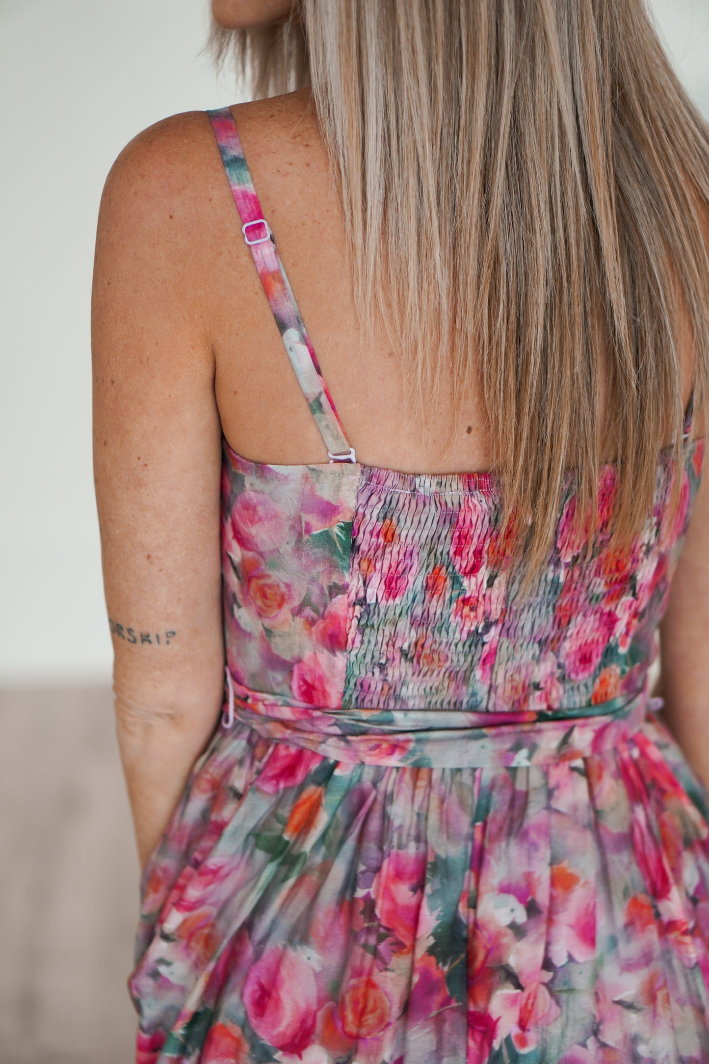 showing off the smocking on the floral dress and the adjustable straps