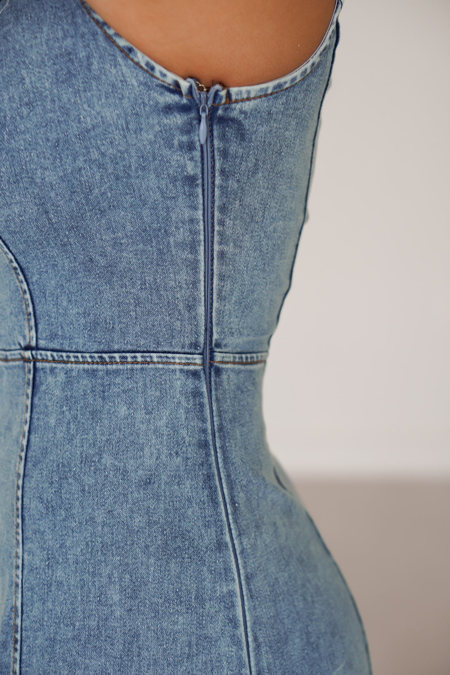 Showing an up close of the zipper on the side of the denim dress