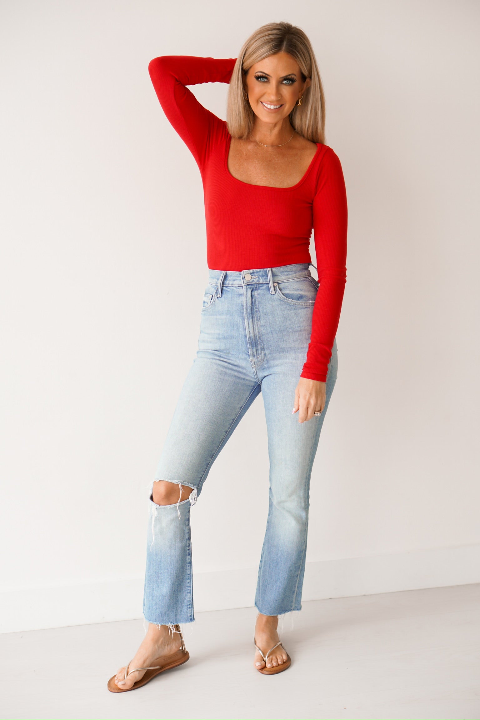 a girl with her hand on her head showing off the long sleeves on the red long sleeve top 