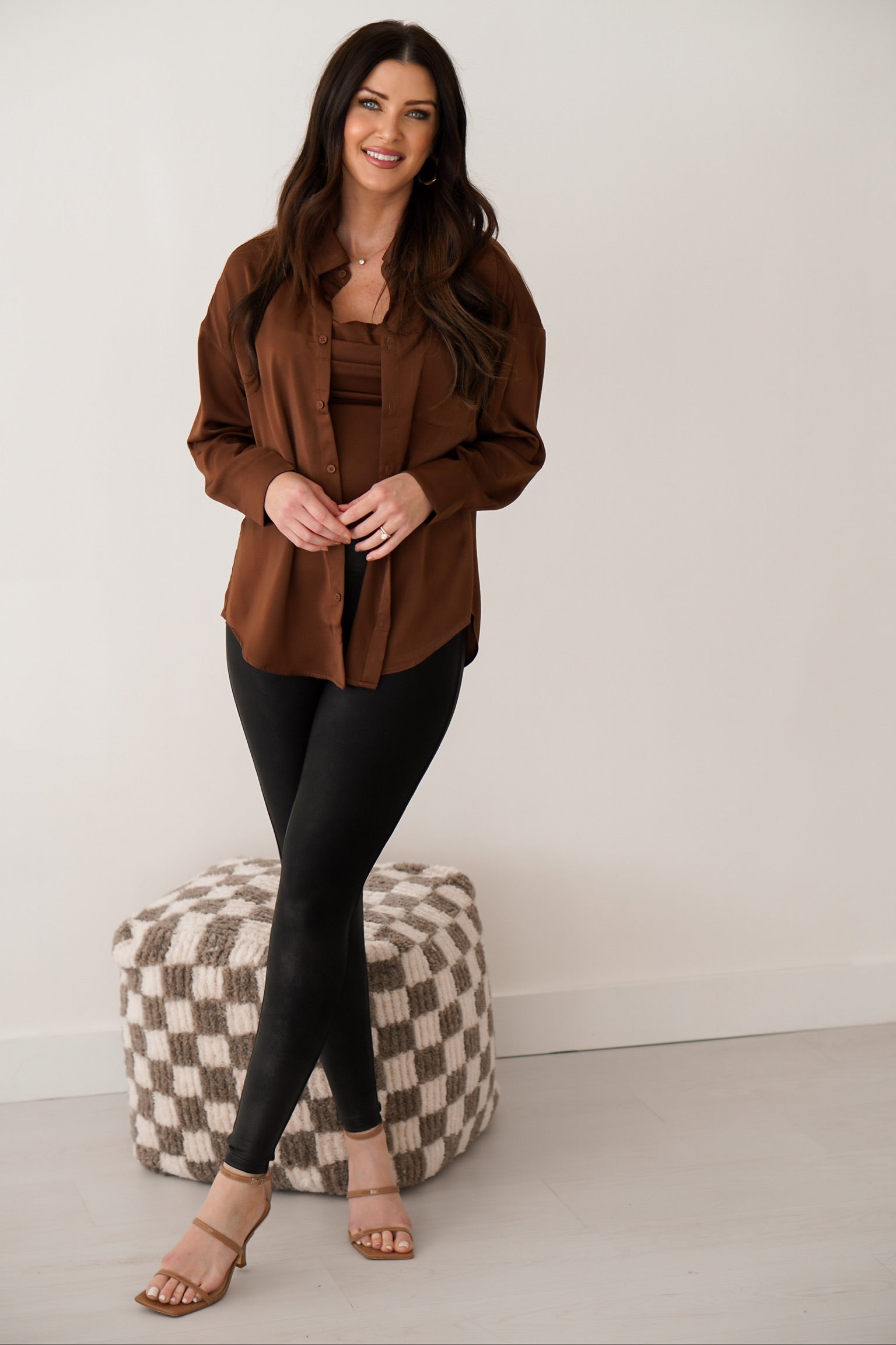Brunette girl wearing chocolate brown silk top set in front of white wall. 