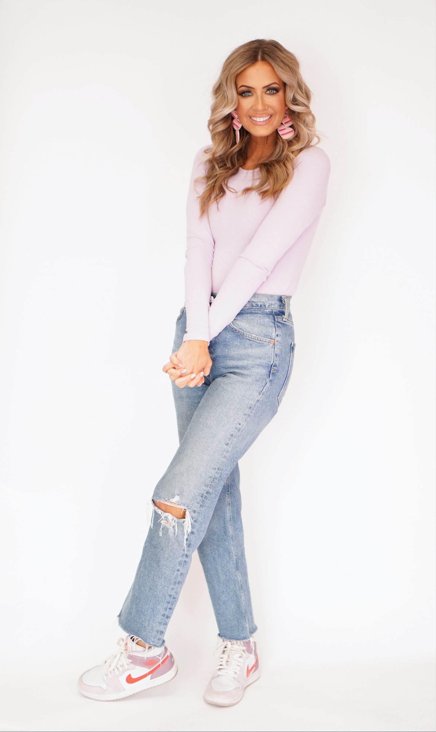 girl showing off her long sleeve bodysuit in lavender with jeans and nike shoes