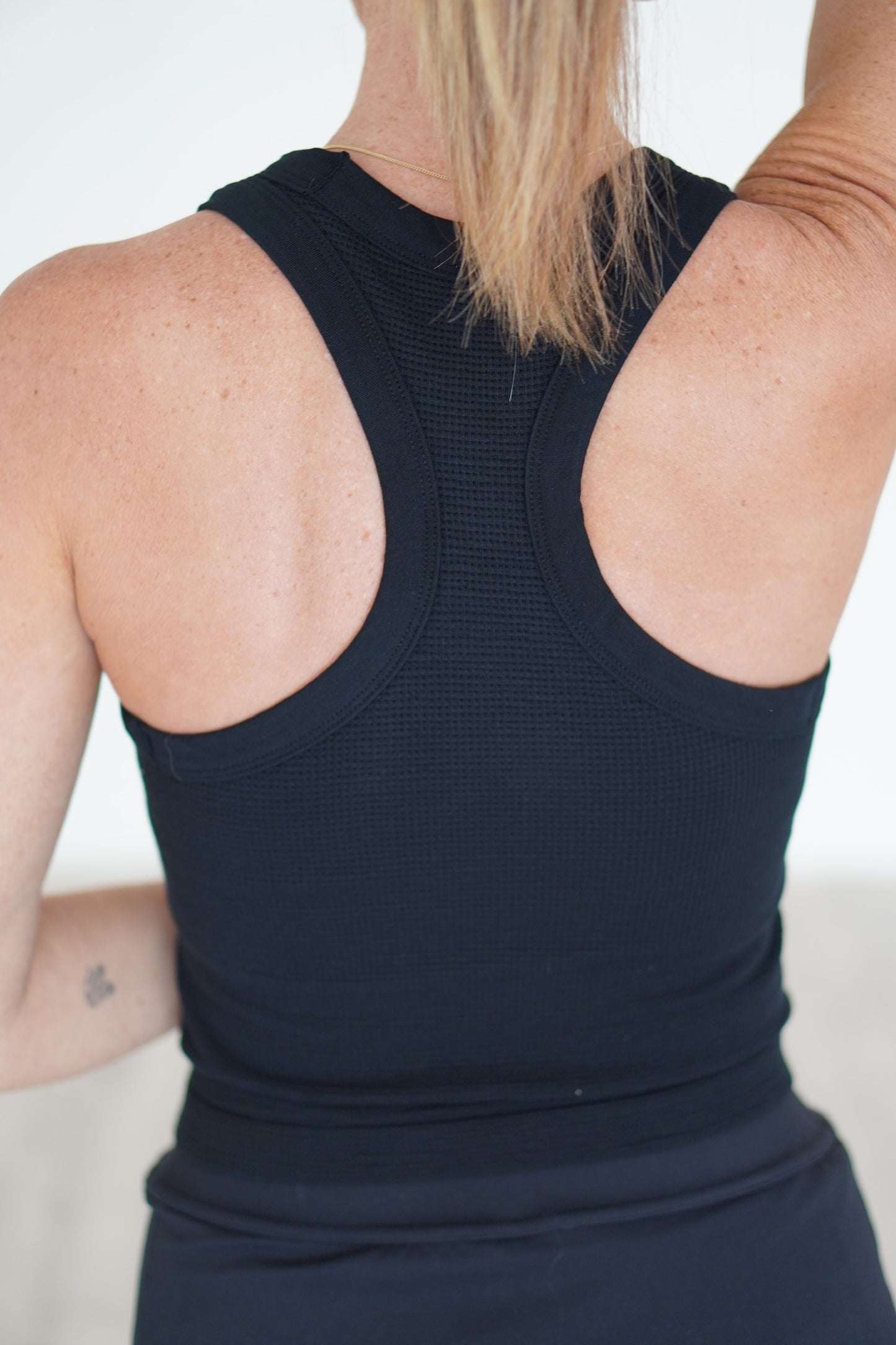 Showing off the back of the black ribbed cropped tank top