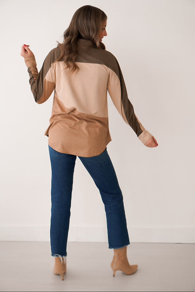 Girl standing in shacket with color block design in rich tones of olive, brown, and cream suede top with hand in pocket. She is standing in front of white wall showing off back of shacket. 
