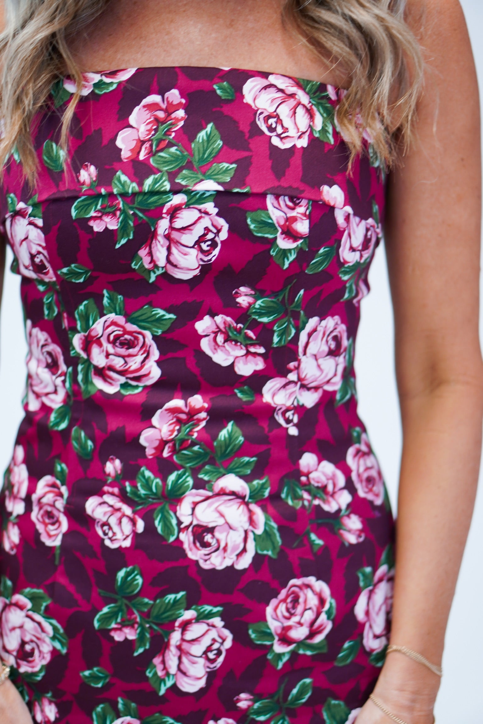 up close shot of details of the tube style dress with floral details. the dress is a dark magenta color