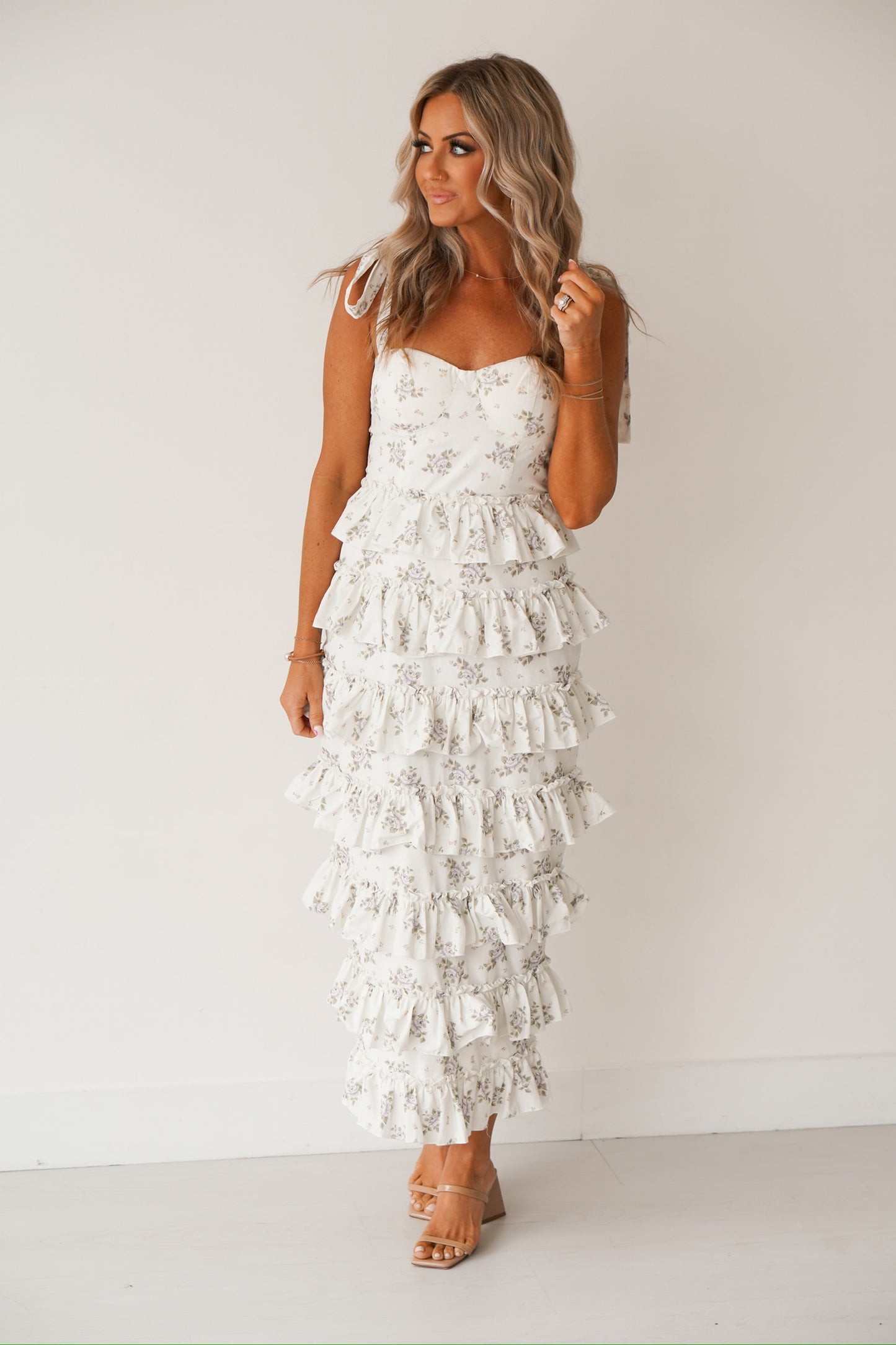 Blonde headed lady standing against a white wall wearing a floral tiered midi dress 