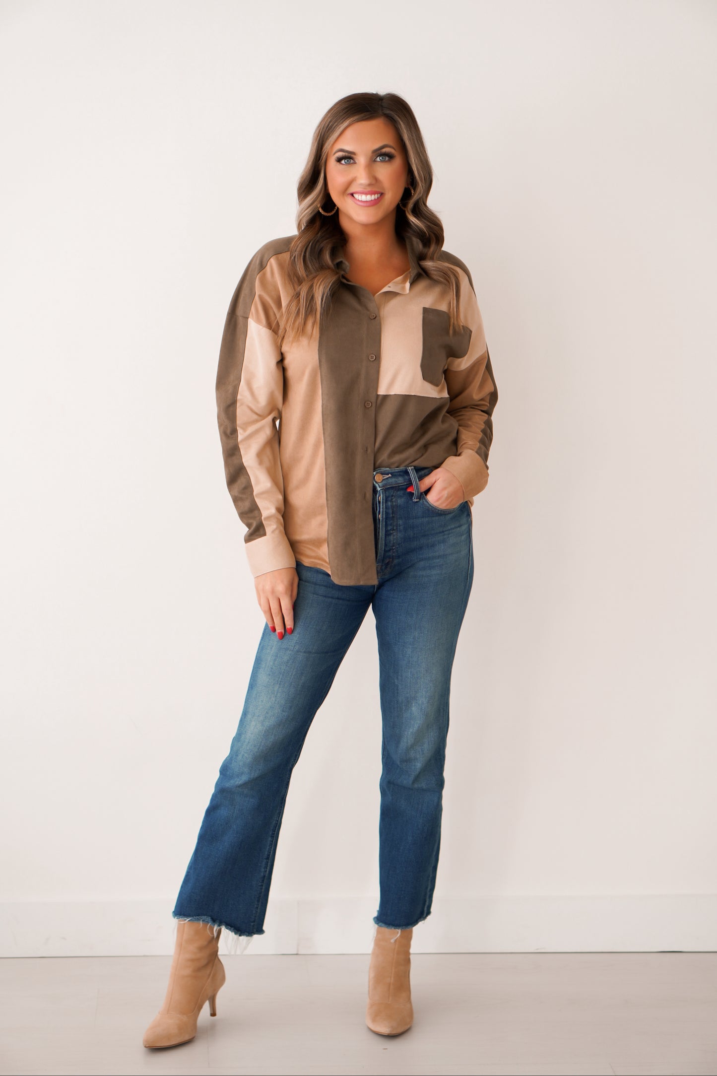 Brunette wearing a color block design shacket in rich tones of olive, brown, and cream she has is paired with jeans. 