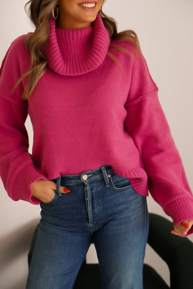 close up of girl wearing turtleneck sweater in a fuchsia color with jeans looking away from the camera