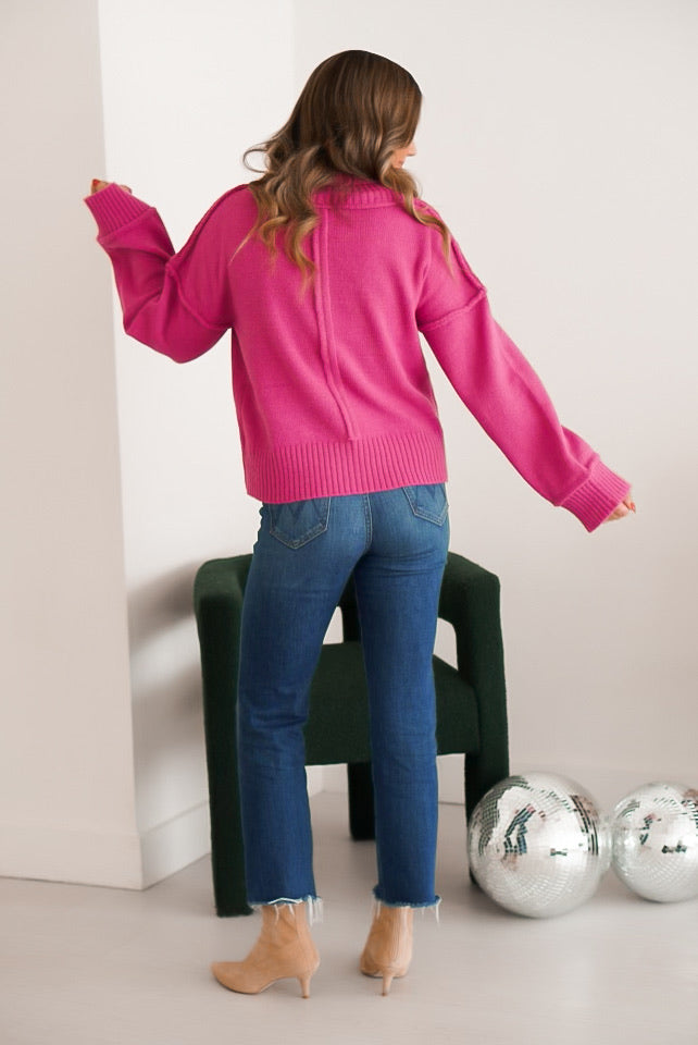 girl standing and posing wearing the turtleneck sweater with jeans and booties picture is taken on the backside to see the back of the sweater
