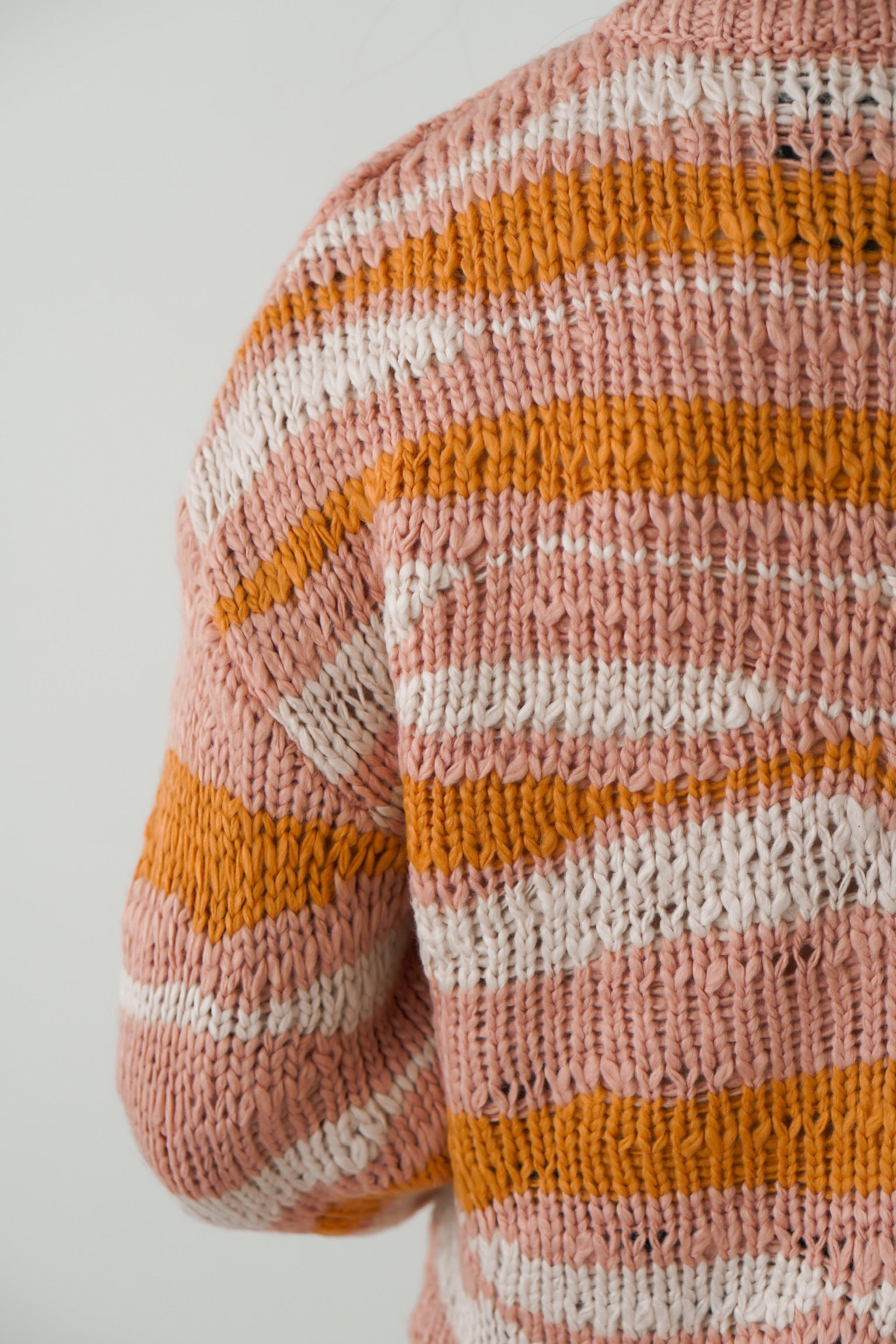 close up shot of sweater that is pink white and orange with a wavy landscape design to it