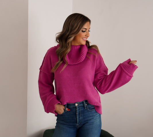 girl wearing turtleneck sweater in a fuchsia color with jeans  looking away from the camera 