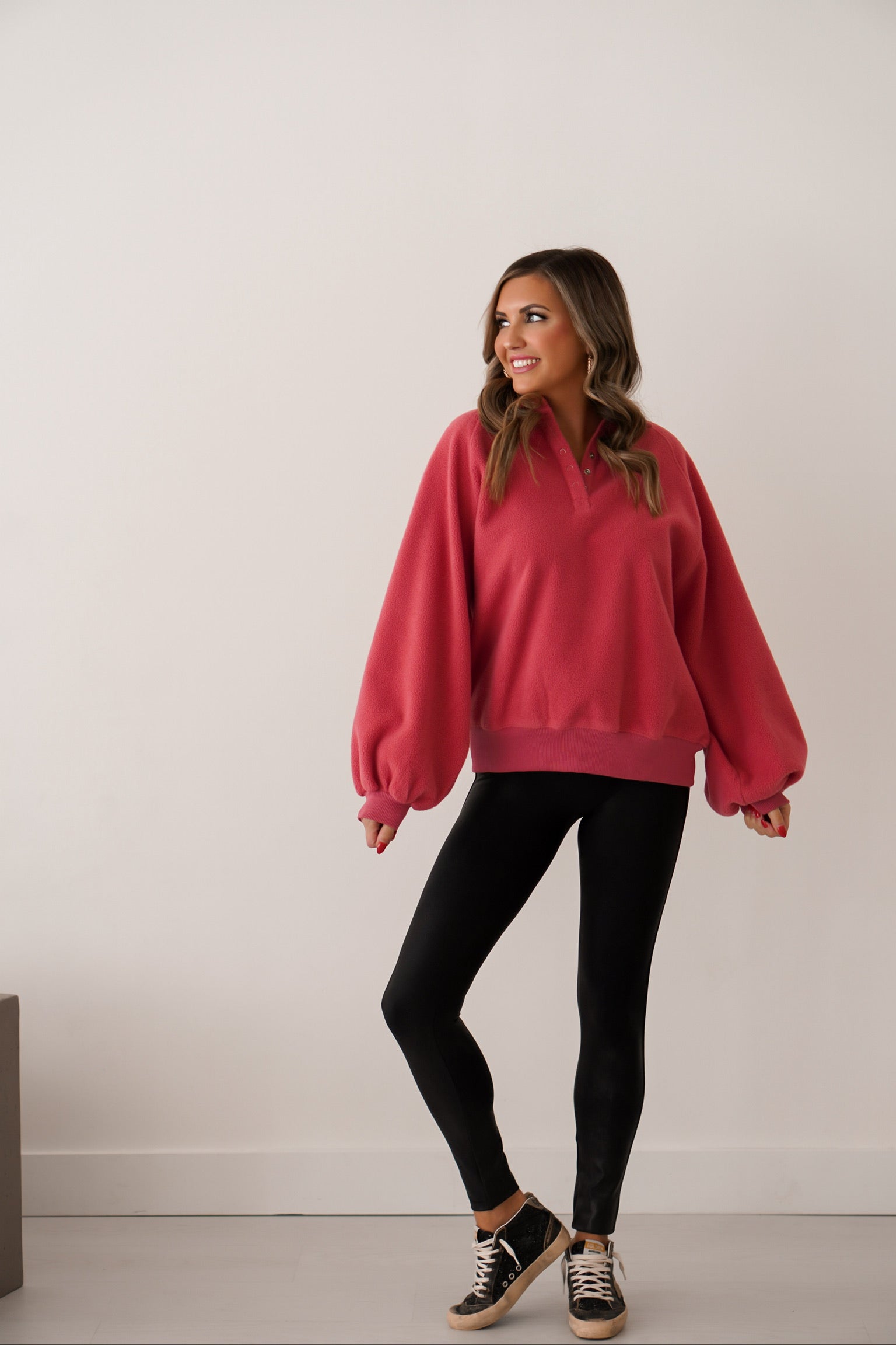 lady standing showcasing the pullover in a berry color with balloon style sleeves 