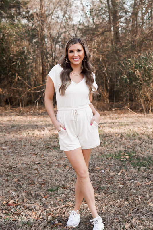 girl showcasing the pockets in a cream cozy romper with v-neck 