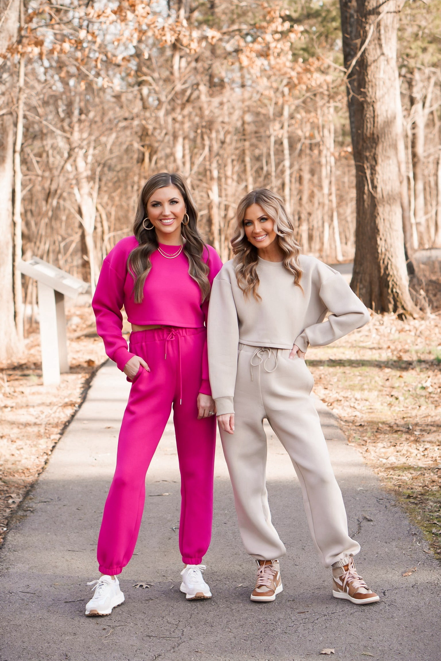 two girls wearing scuba material pullover and joggers. one set being taupe and the other pink.